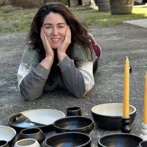 Amanda Bragaw with her finished pots, smiling while laying down
