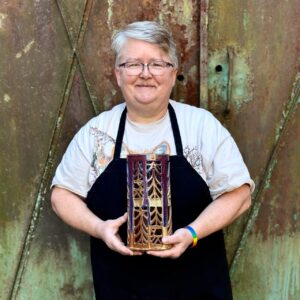 Julia Mann holding finished pot, pierced lantern, glazed in mamo and plum chun