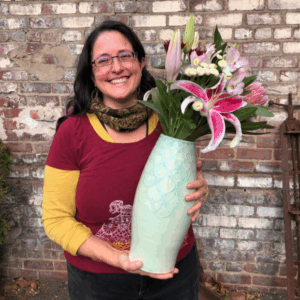 Maria Andrade Troya holding finished pot, vase with flowers
